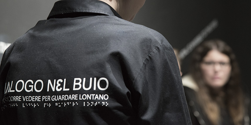 Una guida di Dialogo nel Buio spiega il percorso a un visitatore